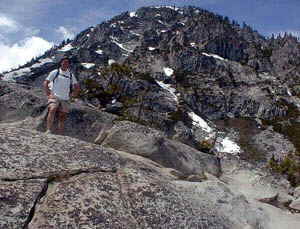 Not atypical "sun" resorts a Tahoe vacation rental guest enjoys a summer hike.  Pictured left a guest pauses to enjoy the view on a hot June day.  Notice the snow still on the mountain and the hiker still in short pants.  Snow fights on a hike in June are one of the many unusual treats of a Lake Tahoe Summer Vacation.